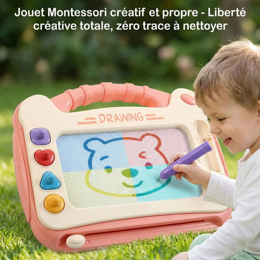 Enfant heureux de 4-5 ans utilisant la planche à dessin magnétique rose